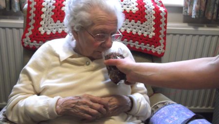 Older woman sniffing a jar of herbs