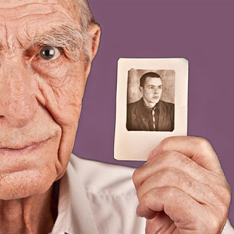 Elderly man holding photograph