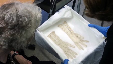 Old woman looks at lace gloves