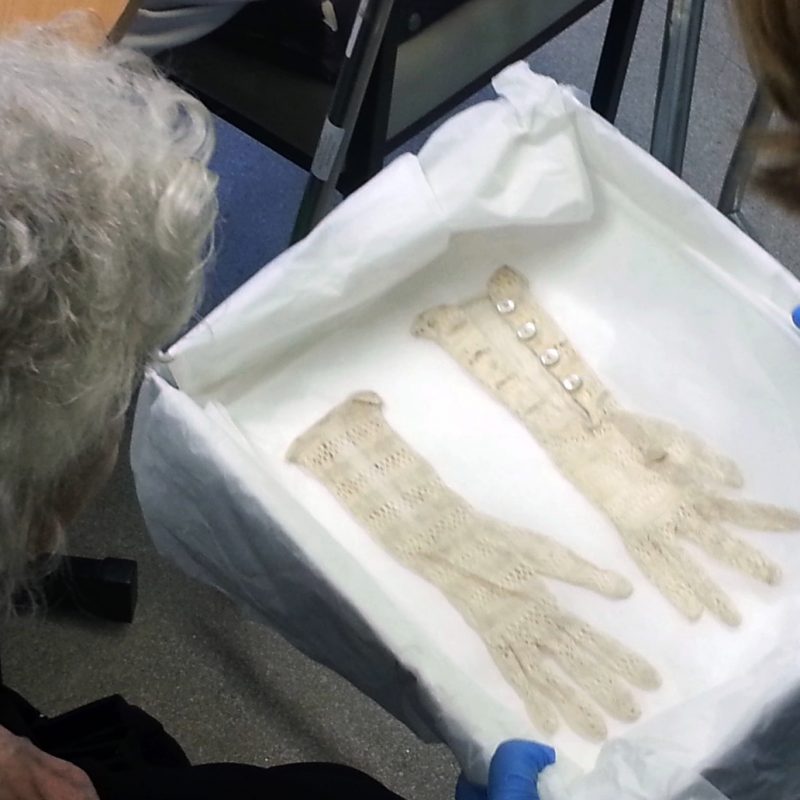 Old woman looks at lace gloves