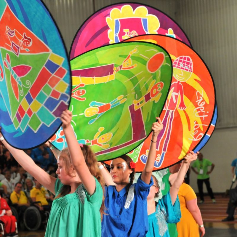 Performers hold painted silk discs