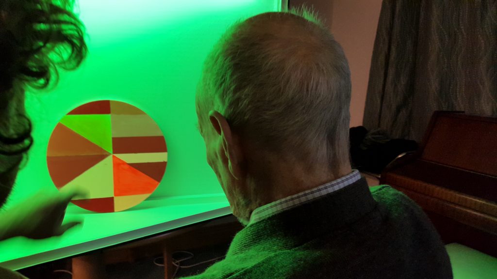 Older person looks at light artwork