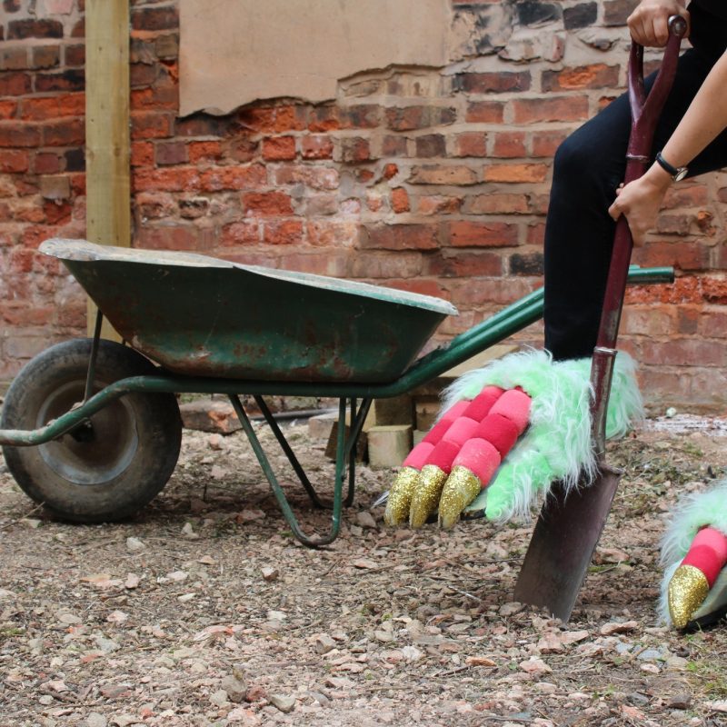 Woman wearing dragon feet digs with spade
