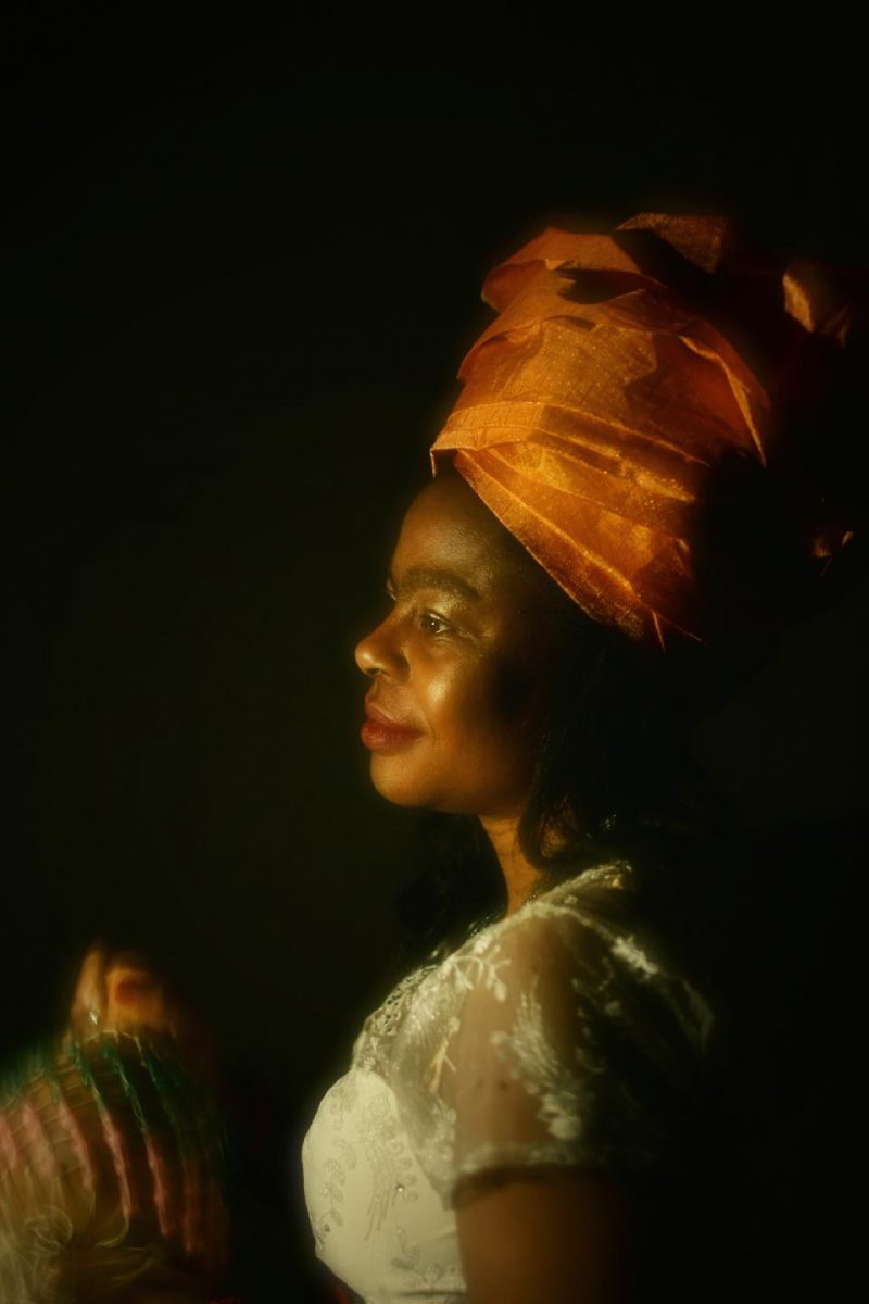 Art photograph of a Nigerian woman holding a flask, wearing a headdress