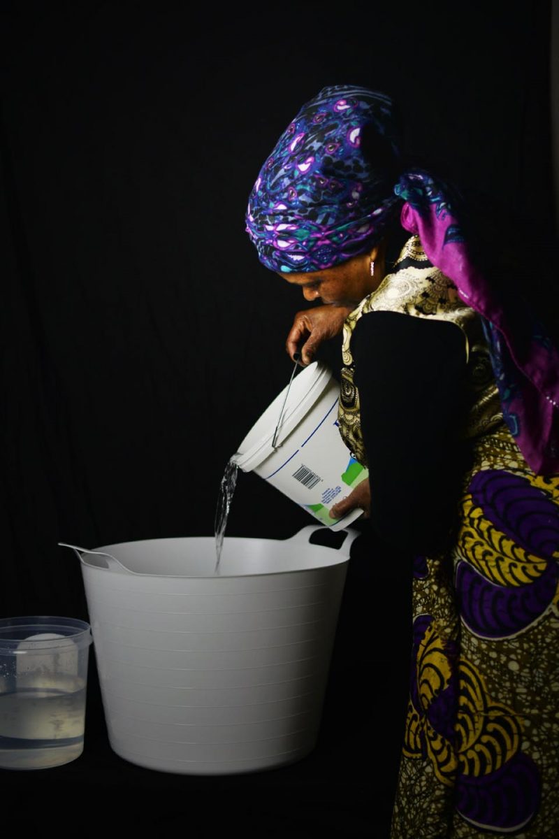 Art photograph of a woman pouring water, wearing a headdress