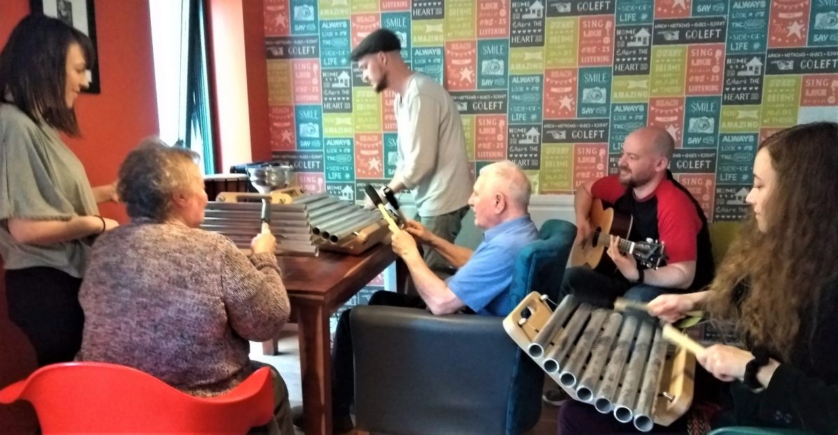 Older people in a care home playing music with musicians