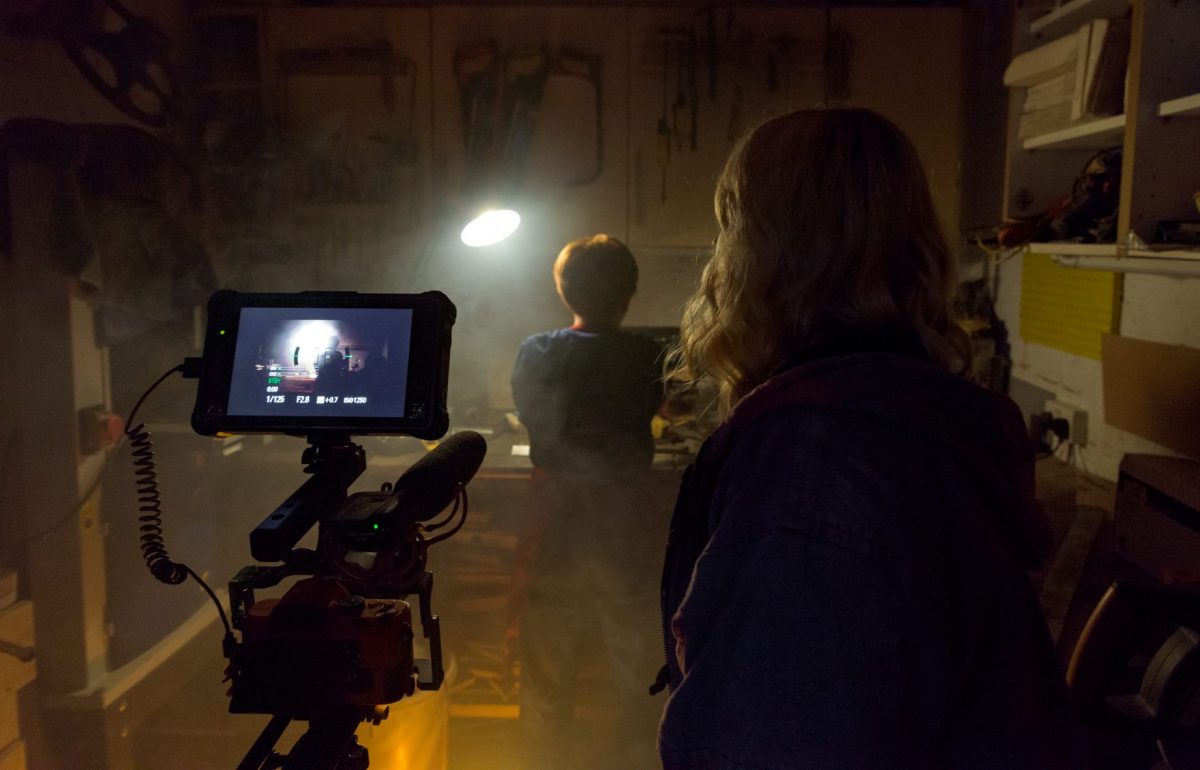 Back of young womans head as she films in a dark shed