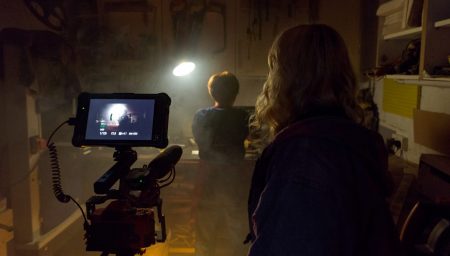 Back of young womans head as she films in a dark shed