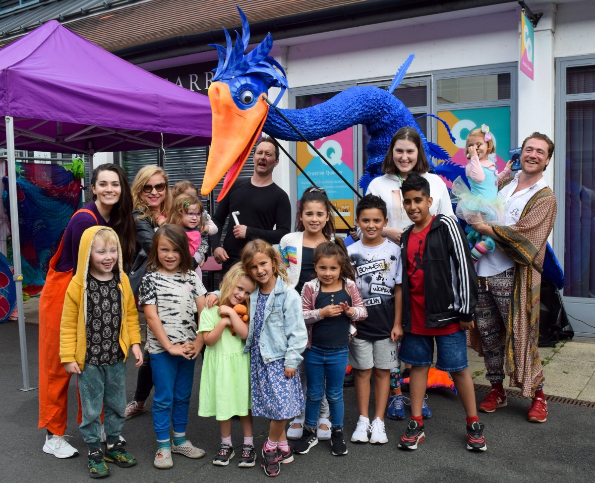 A group photo featuing JINGAH cast member, a giant blue bird puppets and members of the show's audience