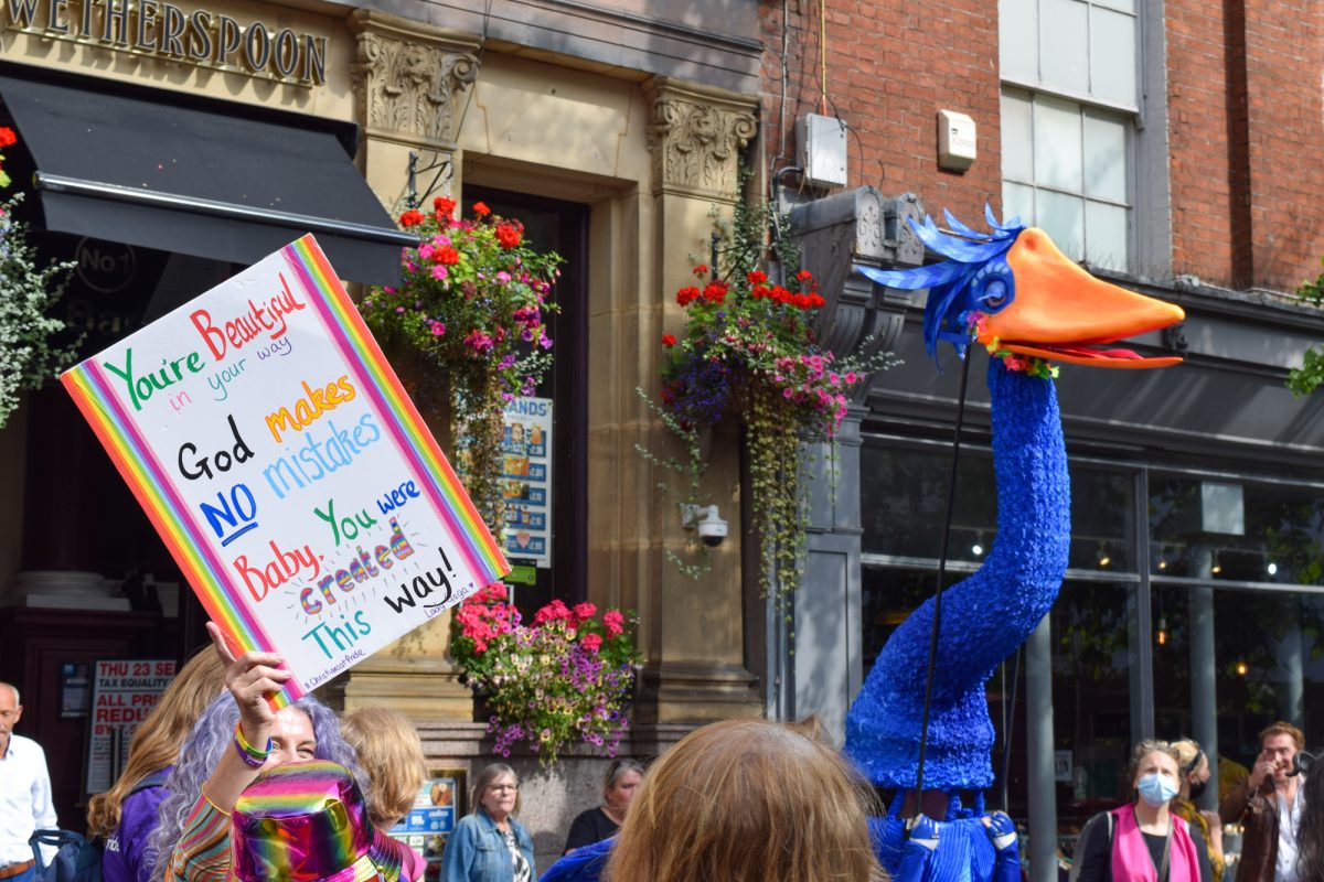 Giant blue bird puppet near a protest plaquard at Nottingham Pride