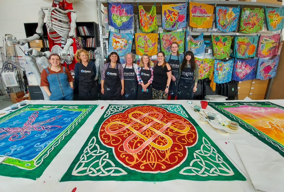 Artists and volunteers surrounded by silks painted with celtic designs