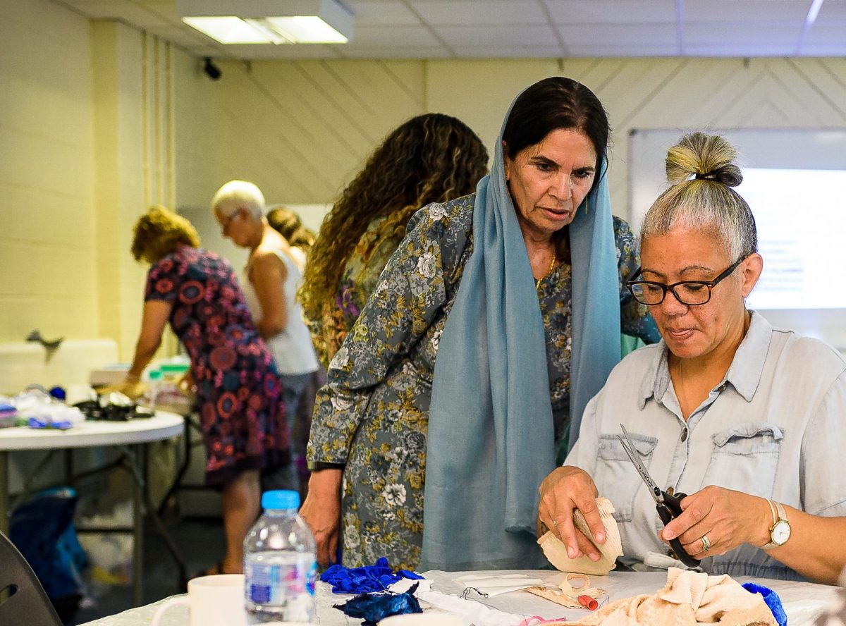 Workshop participants talking whilst cutting textiles