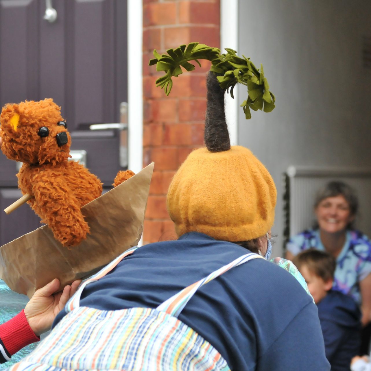 Performer with palm tree hat and teddy bear puppet