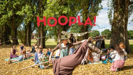 Audience watches performer with stag puppet. Text reads 'Hoopla - a mini festival of ages 0-4'.