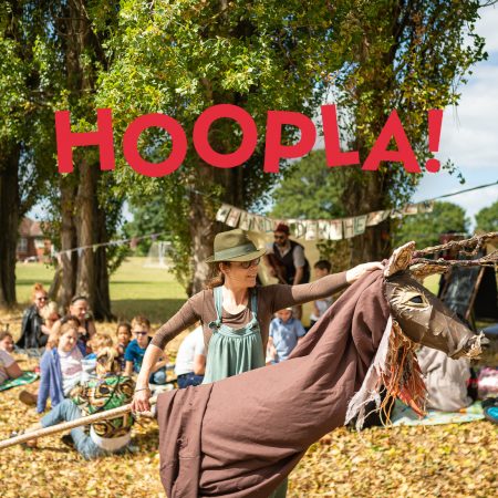 Audience watches performer with stag puppet. Text reads 'Hoopla - a mini festival of ages 0-4'.