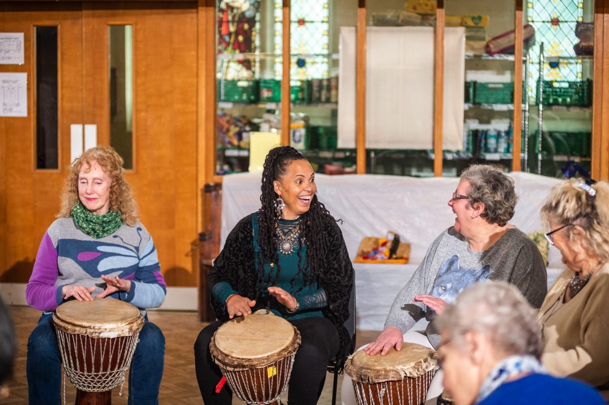 Four women playing djembes in a drum circle