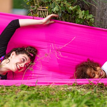 Woman and girl play with pink fabric