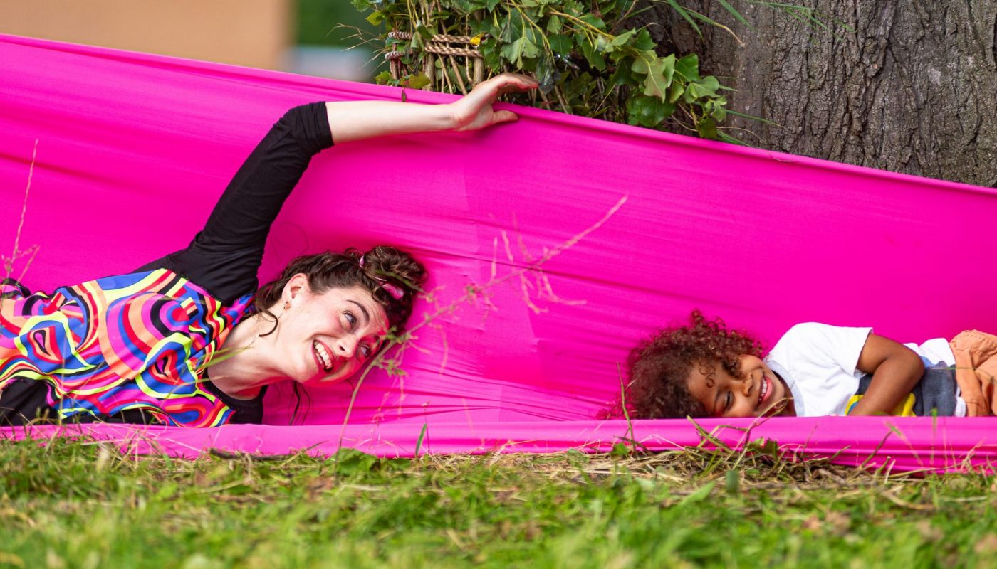 Woman and girl play with pink fabric