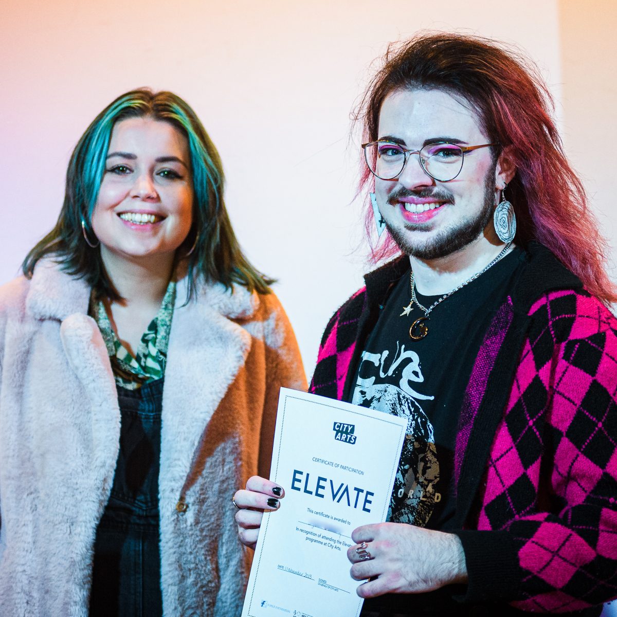 Participant holding a certificate that reads Elevate, standing next to a course leader
