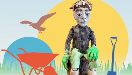 A stylised promotional image featuring a handmade puppet seated on a tree stump. The puppet has large, expressive eyes, a face made from printed text, short straw-like hair, green gloves, and wears a checked shirt, green trousers and white boots. Behind it are simple graphic shapes: a large yellow circle, a smaller blue circle, grass silhouettes, and icons including a red wheelbarrow, a blue spade, and a bird in flight.