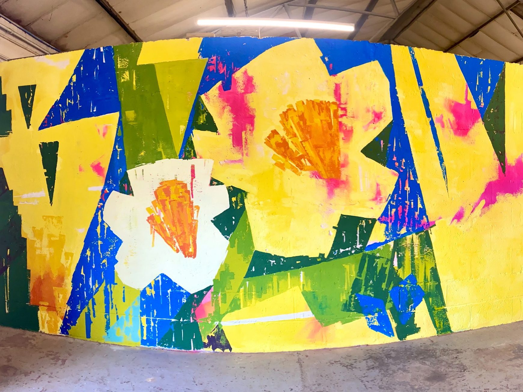 Large indoor mural featuring oversized daffodil flowers in bold yellow, blue, green, white and pink, painted in Natalie Coe’s expressive abstract style.