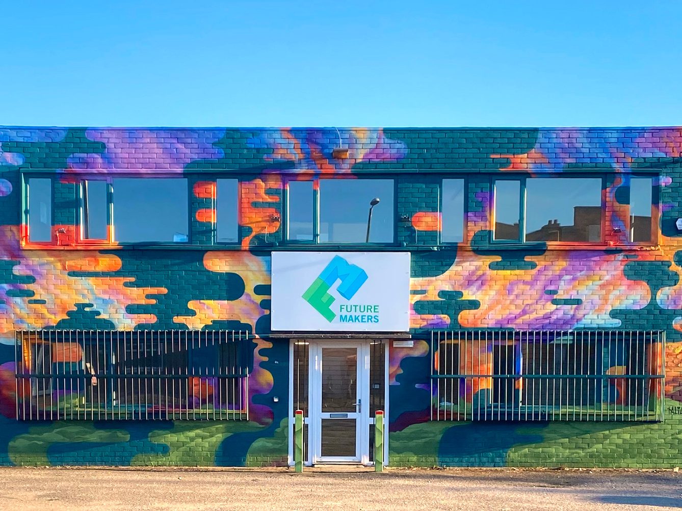 Completed mural by Natalie Coe covering the front of a two-storey building. Flowing abstract shapes in blues, greens, purples and oranges surround the entrance and windows.